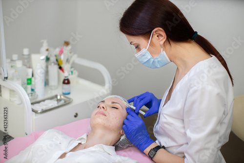 Aesthetic cosmetology in a beauty salon. Female cosmetologist makes rejuvenating botox anti wrinkle injections on the face of a beautiful woman. Skin revitalization, hydration