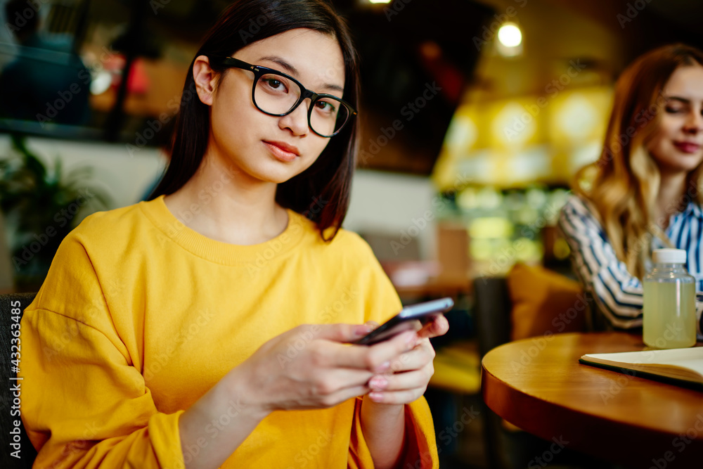 Young woman messaging on smartphone in cafe