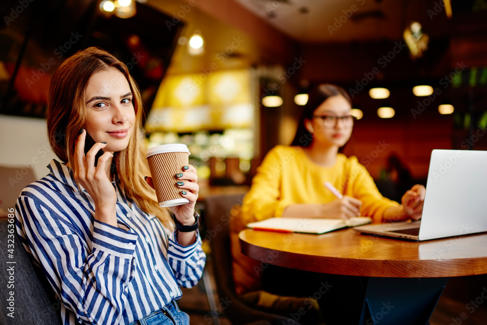 Female colleagues working on laptop in cafe