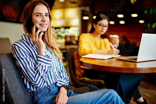 Female coworkers sitting in cafe with laptop and smartphone