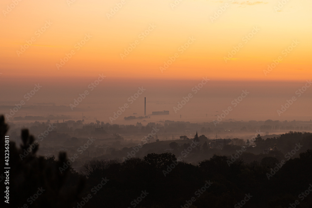 Beautiful sunset over city skyline. Golden hour closeup with layers of fog