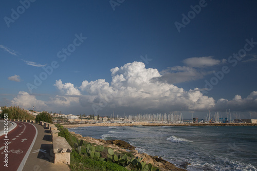 Coastal walk and cycling route in Mediterranean with big cloud and marina in distance photo