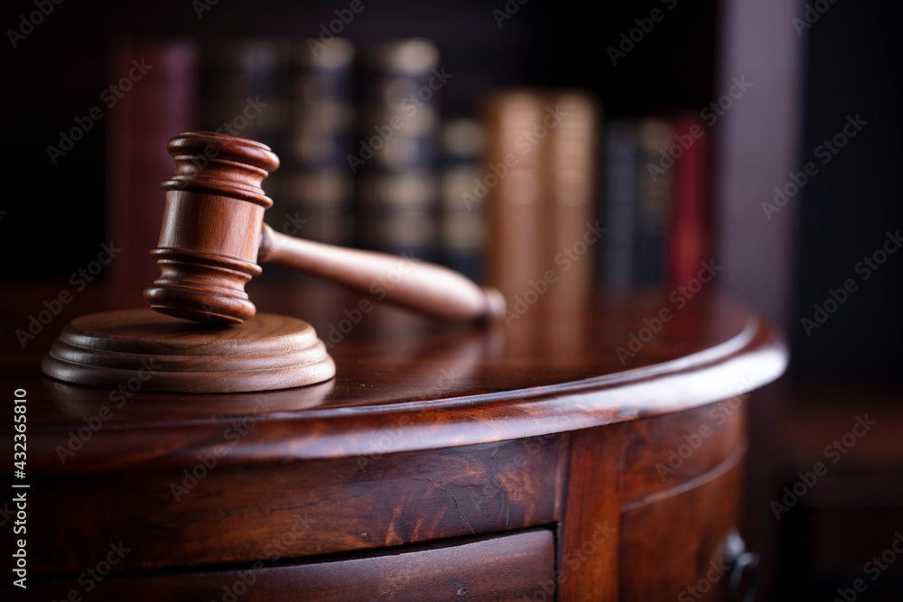 Lawyer office. Gavel on brown shining desk and collection of legal books in the bookshelf. Lawyer office. Gavel on brown shining desk and collection of legal books in the bookshelf.