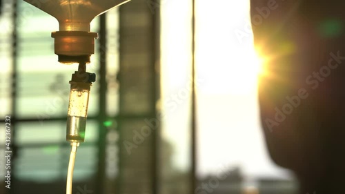 Close up. Saline solution vein drip for patient in the hospital on the day of the sunset. Dripping of iv fluid in hospital.