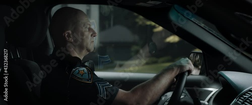 DX Daytime shot of Caucasian American police officer patrolling streets of neighborhood in patrol vehicle. Shot with 2x anamorphic lens photo