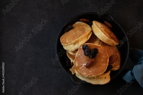 Honey almond raisin pancakes in a black pan on a black background.