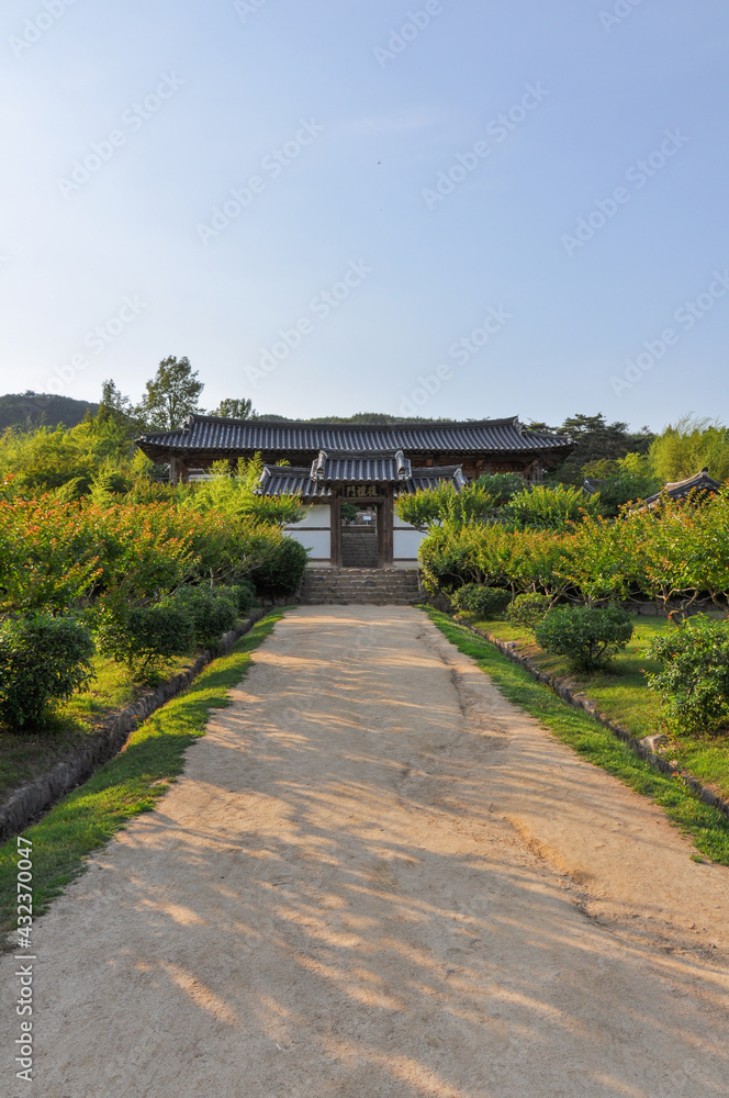 Korean Confucian Academy from Joseon Dynasty era. Path with small trees leading to main gate with pavilion behind. Byeongsan Seowon, Andong, South Korea. Translation: 
