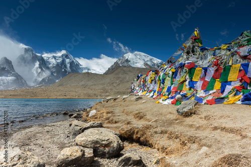 landscape of Gurudongmar Lake with rocks in forte ground and mountain with blue sky in background. Gurudongmar lake one of the highest lake of the world and India.