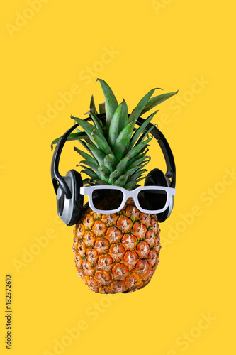 Pineapple hipster in sunglasses and headphones isolated on yellow background, stylish fruit. Summer tropical pineapple. Creative art fashionable vacation concept.