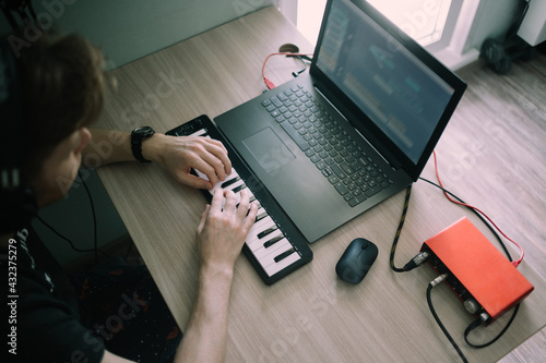 Obraz na plátne Yong music producer or arranger using laptop, midi keyboard, and other audio equ