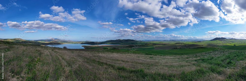 180 degree aerial photo of Ogliastro lake in the heart of Sicily with Etna view. Place of great naturalistic value surrounded by hills planted with cereals. A destination for migratory bird species.