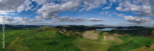 180 degree aerial photo of Ogliastro lake in the heart of Sicily with Etna view. Place of great naturalistic value surrounded by hills planted with cereals. A destination for migratory bird species.