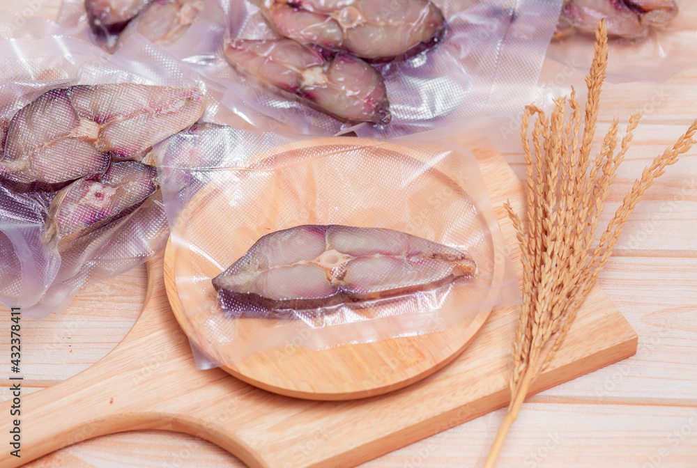 Cutting Dried King mackerel fish in the plastic bag. Packaging sealed of  frozen fish fillet. Famous seafood material in Asia. Salty taste. Ancient  food preservation concept. Stock Photo