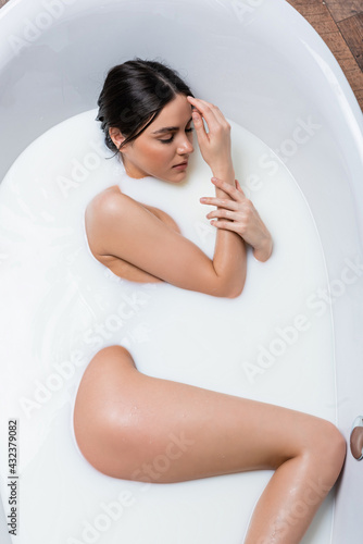 top view of sensual woman with closed eyes taking bath with milk.