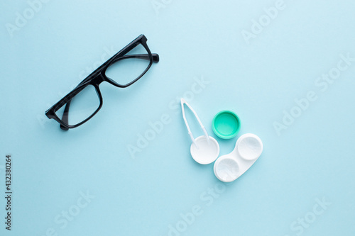 Glasses and accessories for contact lenses: a container for lenses and tweezers on a blue background
