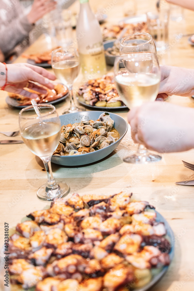 Table full of seafood dishes and glasses with people toasting white wine. Table full of seafood dishes and glasses with people toasting white wine.