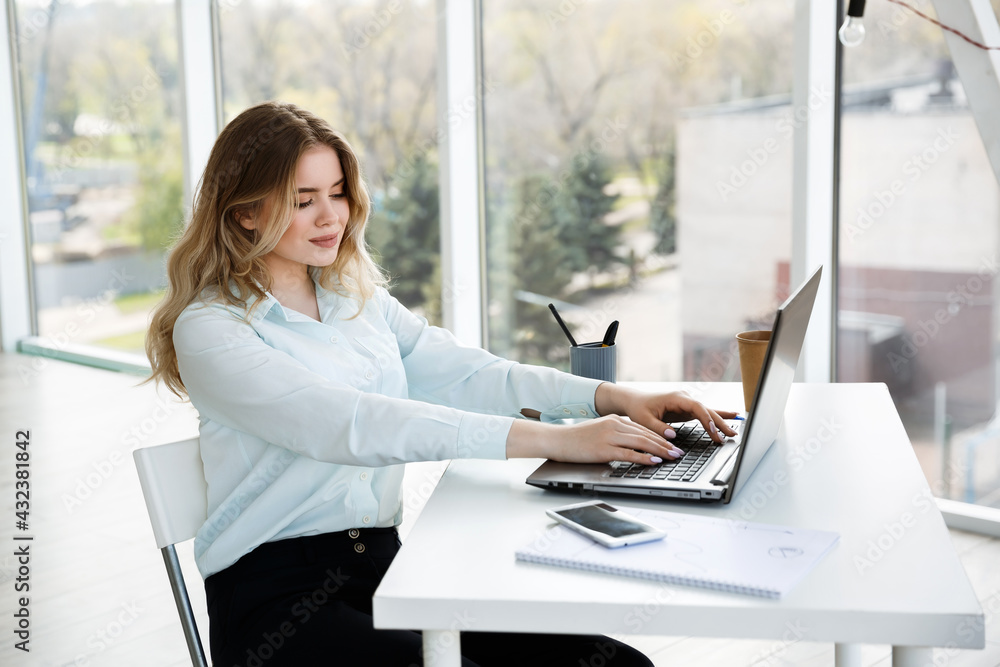 Young beautiful businesswoman works in the office with a laptop. Success Young beautiful businesswoman works in the office with a laptop. Success