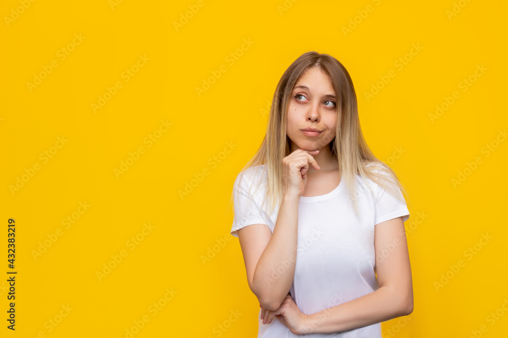 A young caucasian pretty thoughtful blonde woman in a white t-shirt imagines, thinks looking away at empty copy space for ads promo offer quote text slogan isolated on a bright color yellow background A young caucasian pretty thoughtful blonde woman in a white t-shirt imagines, thinks looking away at empty copy space for ads promo offer quote text slogan isolated on a bright color yellow background