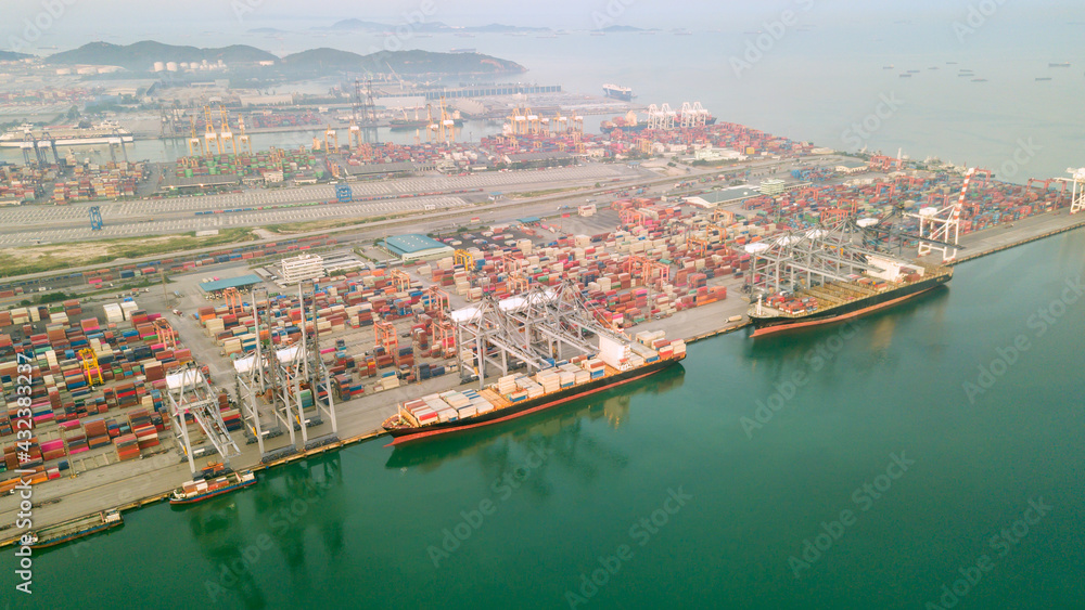Aerial drone view above dockyard. Cargo vessel is loading containers. Professional business logistics and transportation of cargo ship.
