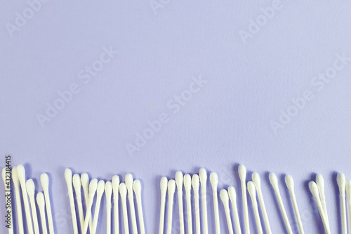 Cotton sticks border, frame on textured purple background. Top view, copy space, line