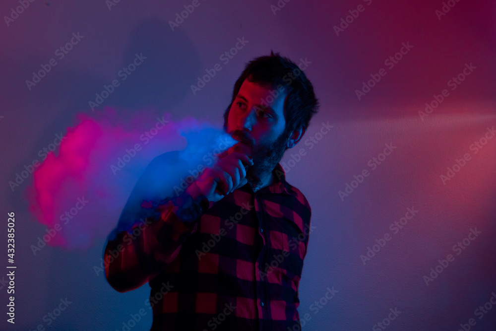 man vaping and throwing smoke with colors on crumpled background. person using electronic cigarette illuminated with pink and blue lights, man vaping and throwing smoke with colors on crumpled background. person using electronic cigarette illuminated with pink and blue lights,