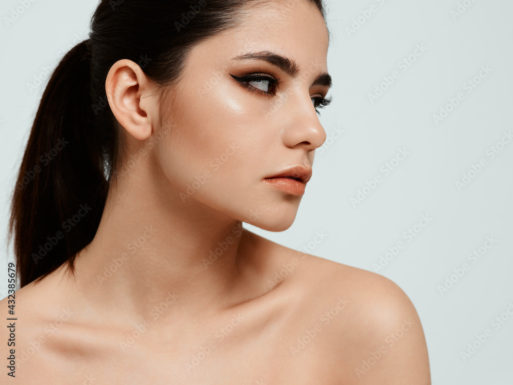 portrait of a woman with makeup on her face on a light background naked shoulders portrait of a woman with makeup on her face on a light background naked shoulders
