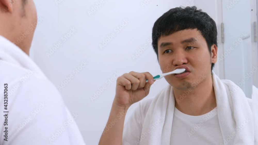 Man using toothbrush to brushing teeth in the bathroom mirror Man using toothbrush to brushing teeth in the bathroom mirror