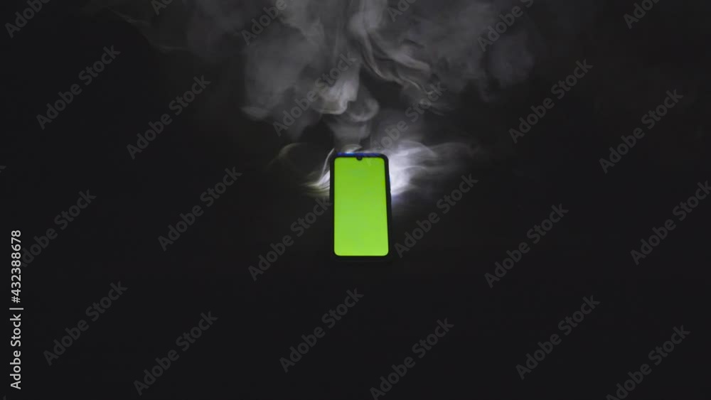 Smartphone avec fond vert sur fond isolé noir avec fumée 