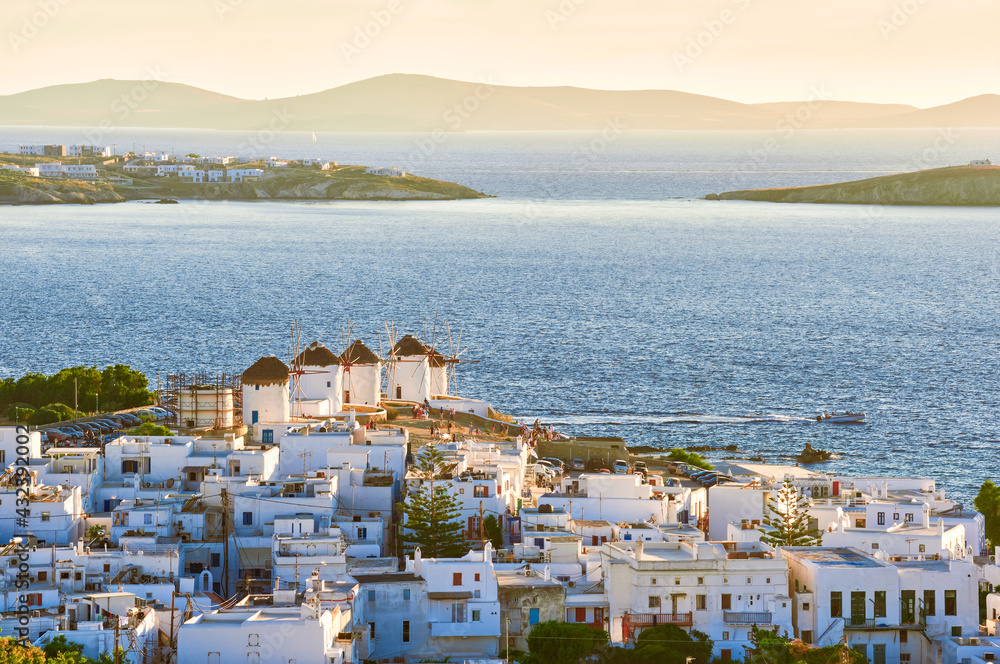 Beautiful view of Mykonos, Greece, famous traditional white windmills on hilltop. Whitewashed house, low sun, summer, iconic Mediterranean destination