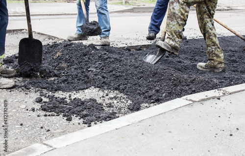 workers laying hot asphalt on the road surface