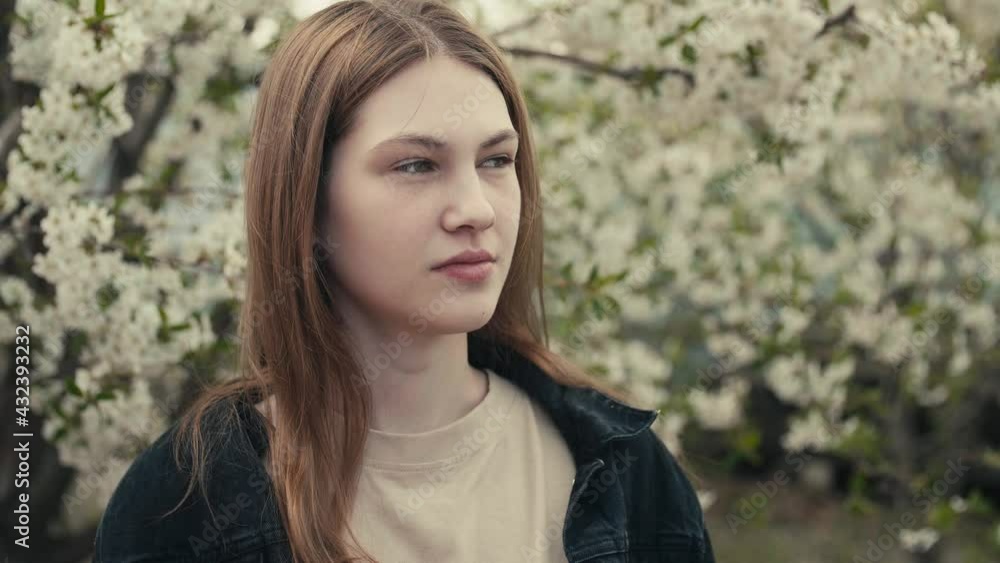 Beautiful young woman in a dark denim jacket in the spring garden in bloom, spring cherry trees blossom, harmony with nature, seasonal spring scene. Slow motion video. Beautiful young woman in a dark denim jacket in the spring garden in bloom, spring cherry trees blossom, harmony with nature, seasonal spring scene. Slow motion video.