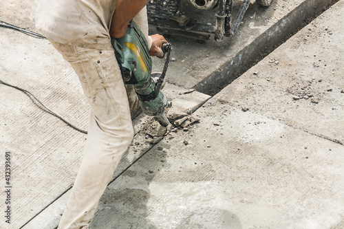 Construction worker using jackhammer drilling concrete surface