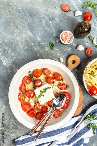 Trending fetapasta hot salad with baked tomatoes and feta. Preparation of ingredients for feta pasta. vertical image, place for text, top view photo