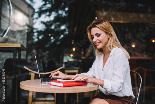 Stylish female freelancer working on project on laptop on terrace of cafe © BullRun