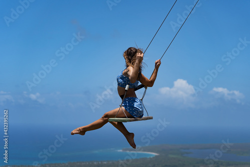 Young beautiful caucasian woman on the rope swing with sea and sky background. Concept of Vacation and travel  © Hladchenko Viktor