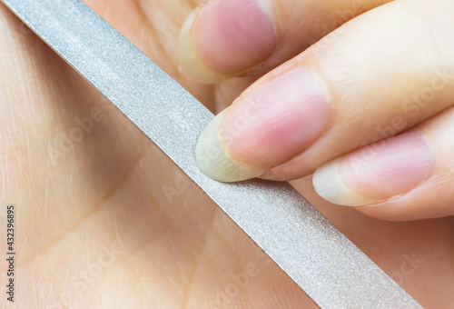 Woman makes herself a manicure at home, cuts her nails. Close-up. Nails cutting process. Nail file macro.