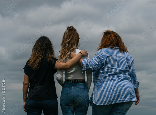 Female friends looking at the horizon from behind in a park