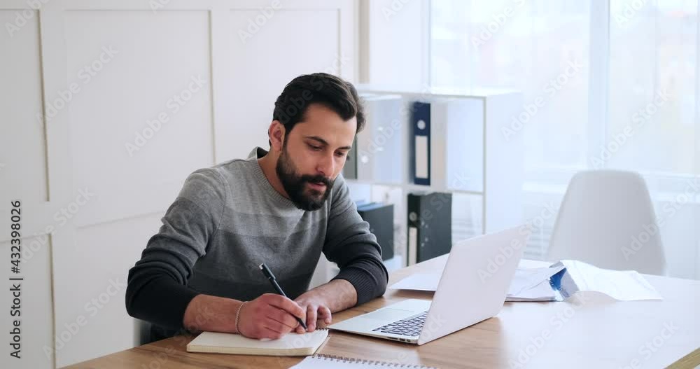 Businessman working on laptop and writing notes in diary at office Businessman working on laptop and writing notes in diary at office