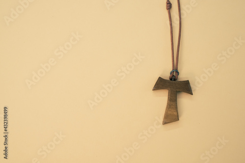 Closeup shot of a wooden tau cross necklace isolated on a brown background