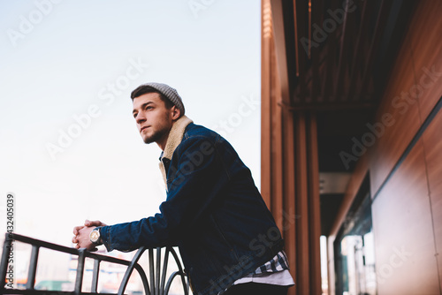 Hipster man looking away standing on terrace