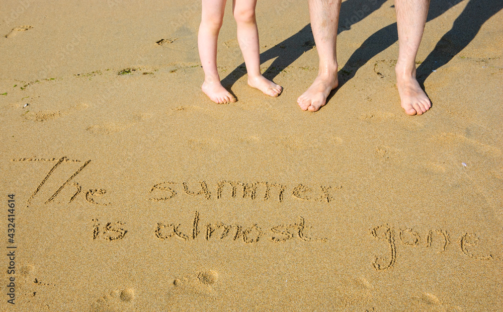A sentence written on the sand of a beach THE SUMMER IS ALMOST GONE