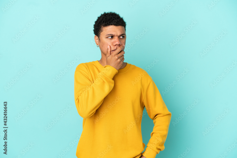 Young African American man isolated on blue background having doubts and with confuse face expression Young African American man isolated on blue background having doubts and with confuse face expression