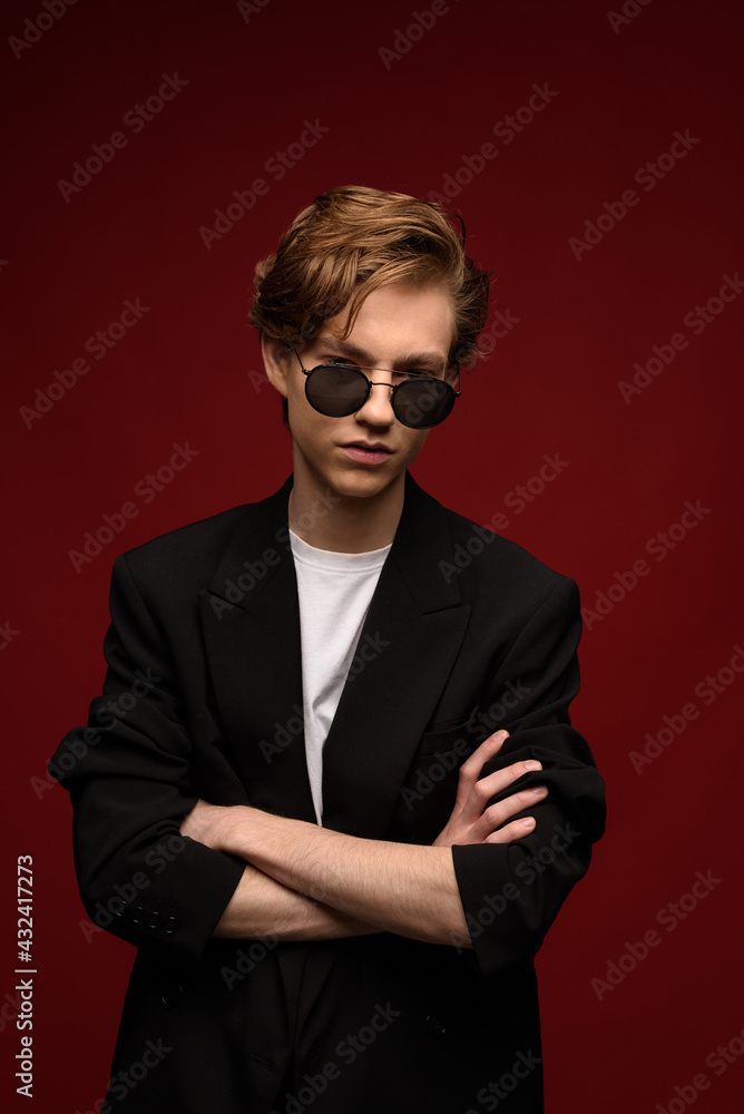 Fototapeta premium guy in black glasses, white t-shirt and black suit. beautiful, long blonde hair. serious facial expression