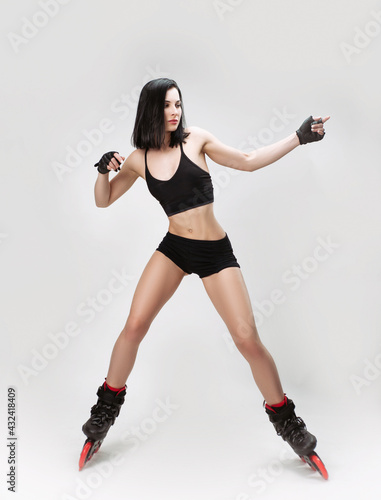 slender woman in sports short clothes on roller skates dancing on a white background