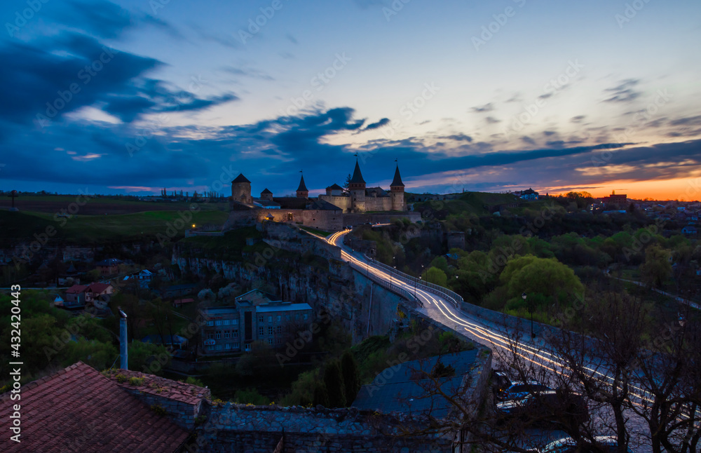 View on the Kamianets-Podilskyi сastle in the evening. Beautiful stone castle on the hill on the sunset. Clouds in the darkening sky above the castle. Long exposure. Ukraine