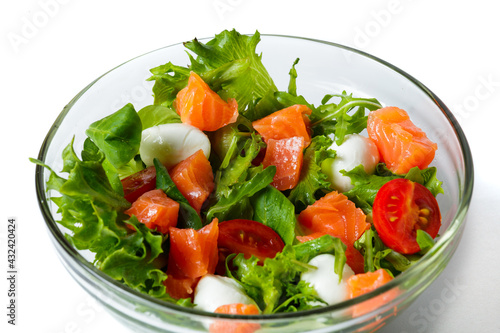 Healthy food concept. Fresh salad with salmon, arugula, cherry tomatoes and lettuce isolated on white. transparent dishes with food. Advertising poster. Close-up view.