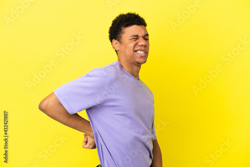 Young African American man isolated on yellow background suffering from backache for having made an effort © luismolinero