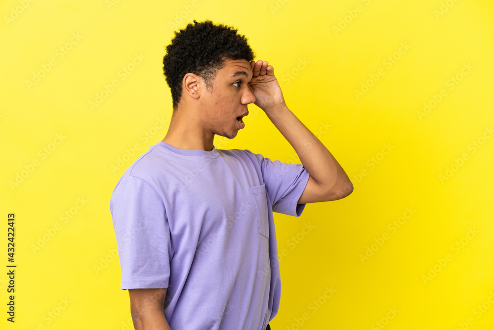Young African American man isolated on yellow background with surprise expression while looking side Young African American man isolated on yellow background with surprise expression while looking side