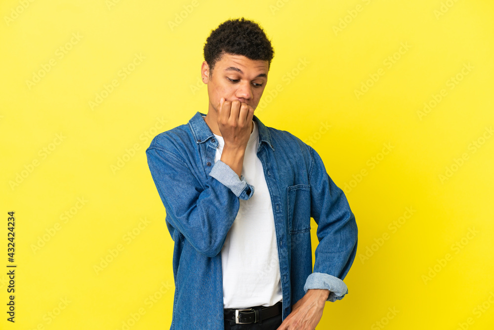 Fototapeta premium Young African American man isolated on yellow background having doubts