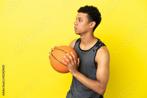 African American man isolated on yellow background playing basketball © luismolinero